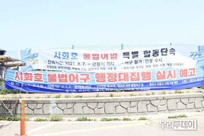시화호 불법어업단속 현수막 . 재)안산환경재단 이 시화호 상류에 불법 설치된 어망 철거 작업에 나섰다 (사진=박현정기자)